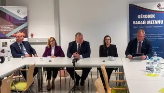 Pięć osób siedzi przy stole w sali konferencyjnej.