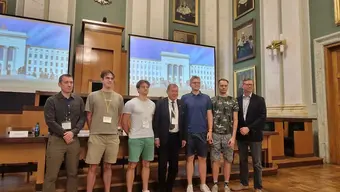 Image of the students awarded in the hackathon posing for a photo with the Rector and a representative of the US side in the AGH University main assembly hall