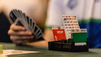 A decorative photograph of a person holding a deck of cards playing bridge.