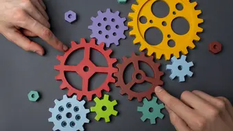 Image of a person touching colorful gear wheels with their index fingers