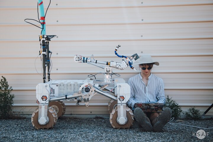 Image of a person sitting next to a Martian rover