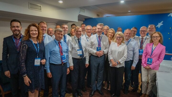 Image of a large group of people with lanyards with Forum IDs in front of the official backdrop of the Economic Forum in the shades of blue; pictured in the photo are Minister Wieczorek and Rector Lis