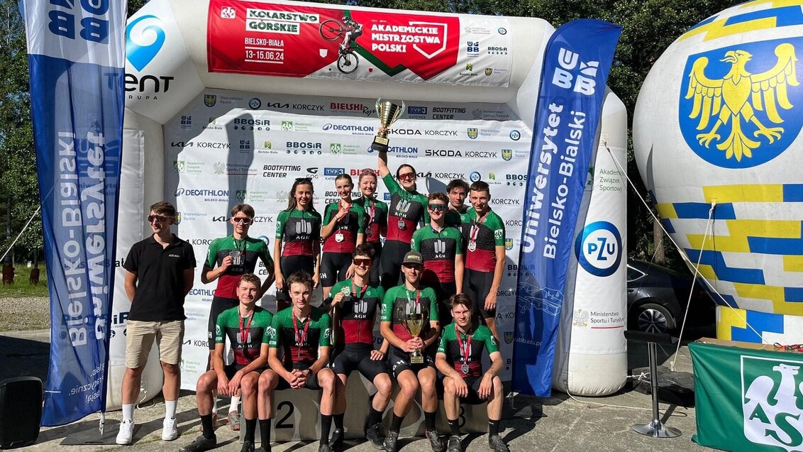 Image of the AGH University mountain biking team pictured on a podium with two cups