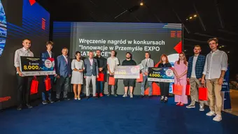 A group of people including winners of a competition posing for a photo with awards