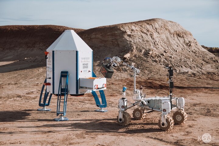 Image of a rover next to a device located on a desert