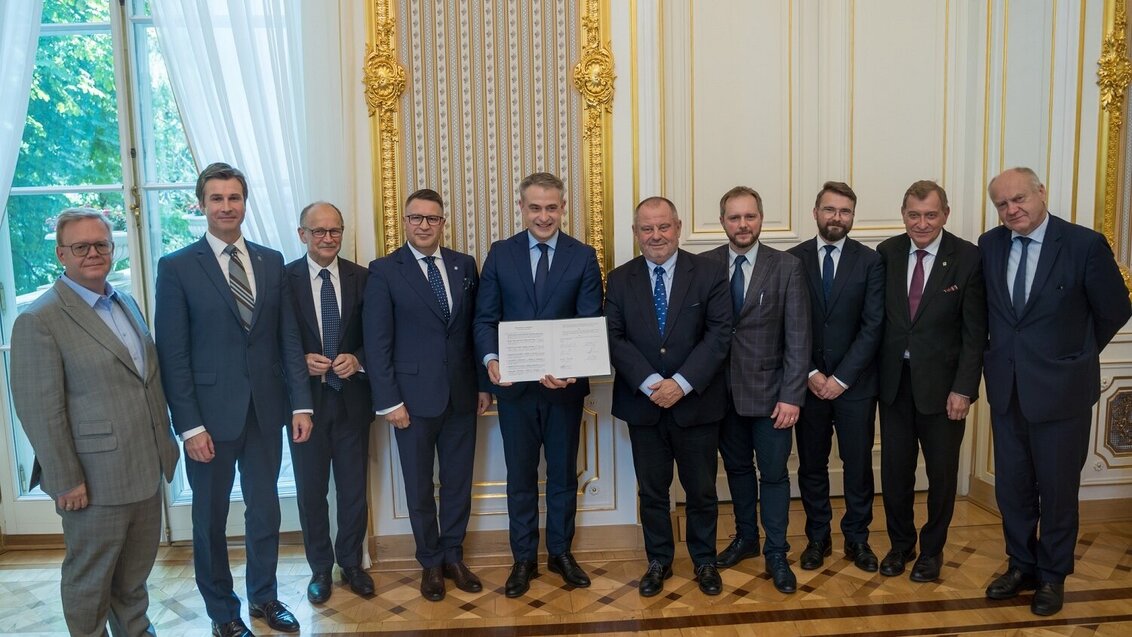 Image of some rectors of Polish universities and parties which shall cooperate on the AI Forum posing for a photo with the Minister of Sigital Affairs holding the agreement