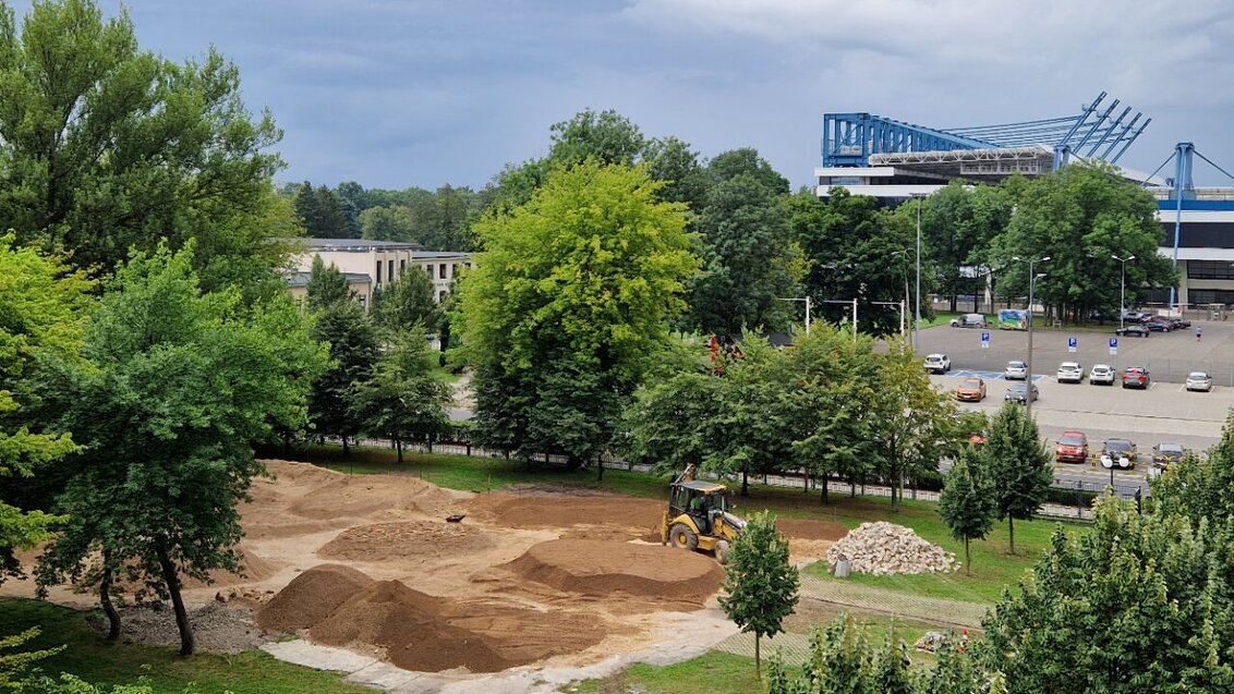 Zdjęcie panoramiczne z lotu ptaka przedstawiające widok na budowany na kampusie tor. Widoczne usypane z czerwonej ziemi nierówności i przeszkody.