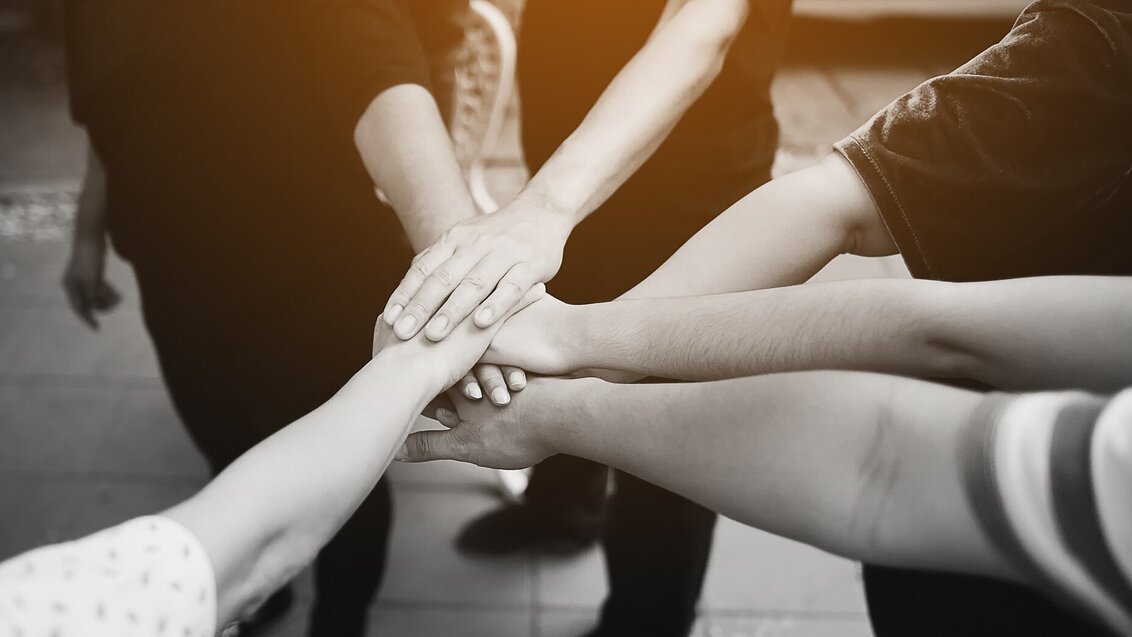 a black and white image of people placing hands on top