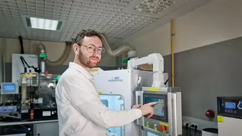 Image of a scientist in a lab touching a screen of a laboratory device