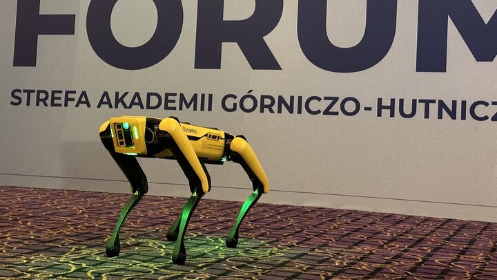 Image of a yellow robotic dog, quadroped, standing on four legs with a small green light in its front part