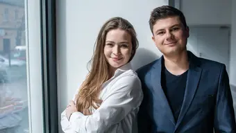 An image of two young people, a woman and a man, dressed in business casual.
