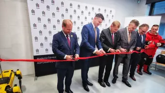 Image of a group of six people cutting a red ribbon in front of the AGH University photo backdrop